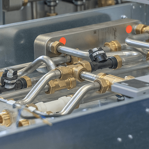 Nahaufnahme einer Wohnungsstation mit metallenen Rohren und Ventilen.