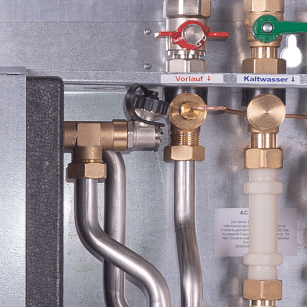 Close-up of a boiler replacement station with stainless steel pipes, valves and plate heat exchangers.